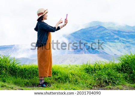 A woman with a smartphone enjoying a trip in lush nature