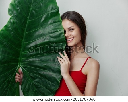woman with open mouth in a swimsuit holding a green leaf in front of her