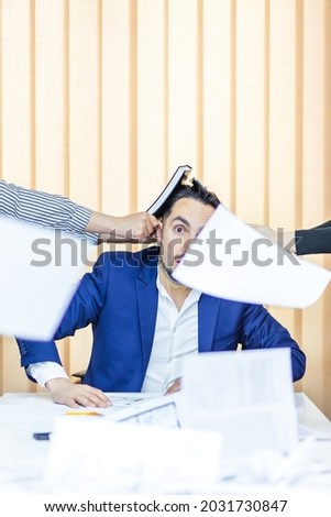 Photo of a businessman in blue suit having a lot of work sitting in the office.