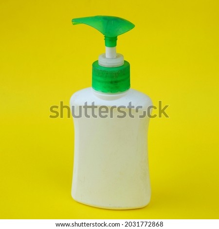 White bottle of hand sanitizer isolated on yellow background