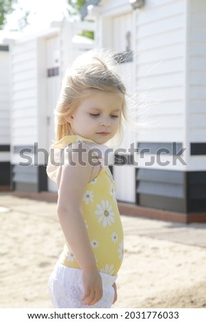 Portrait of sweet toddler girl on the beach in front of changing room.
