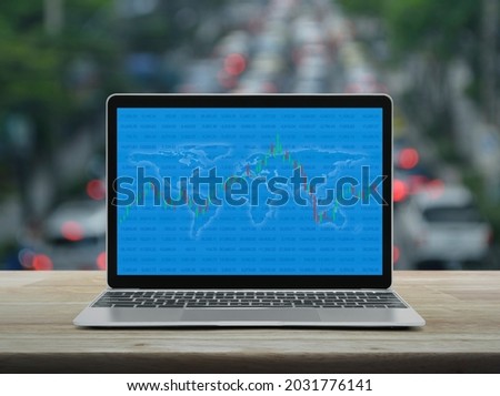 Trading graph of stock market with world map and graph on modern laptop computer on table over blur of rush hour with cars and road, Investment online concept, Elements of this image furnished by NASA