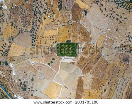 Aerial view on a green football field during drought on sifnos island, Greece 