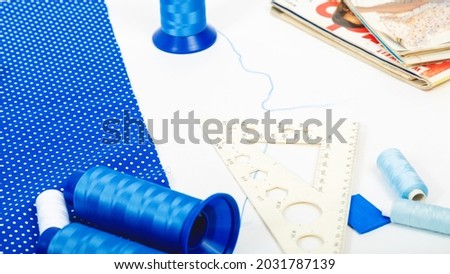 sewing business. Tailor's workplace with threads, scissors, template, spools, blue fabric. white background top view space for text in the frame. Tailoring concept
