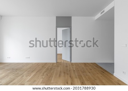 Empty minimalist modern room with white walls, opened grey door, grey floor tiles and oak wood floor
