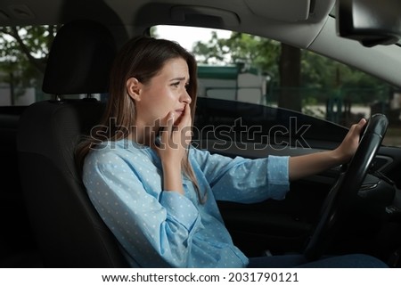 Stressed young woman in driver's seat of modern car