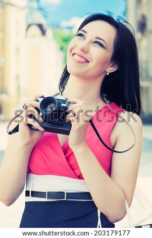 beautiful young woman taking photos with vintage camera on a city street