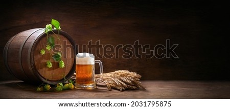 mug of beer, wheat ears, hops and beer barrel on a wooden background Royalty-Free Stock Photo #2031795875