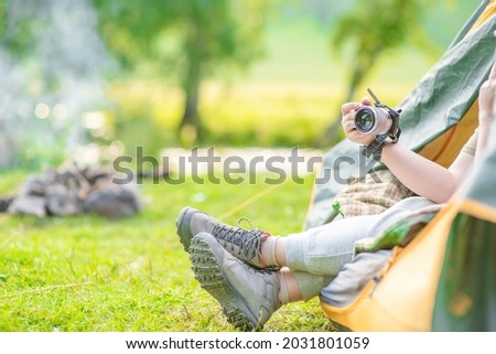 Woman enjoys the rest in the tent and take photo of nature. Empty space for text