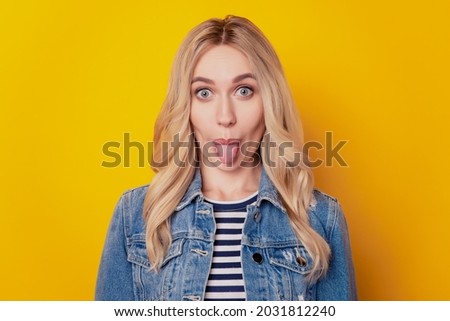 Portrait of funky crazy girl protrude tongue look camera have fun on yellow background