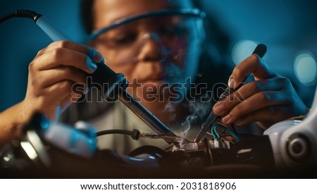 Young Teenage Multiethnic Schoolgirl is Studying Electronics and Soldering Wires and Circuit Boards in Her Science Hobby Robotics Project. Girl is Working on a Robot in Her Room. Education Concept. Royalty-Free Stock Photo #2031818906