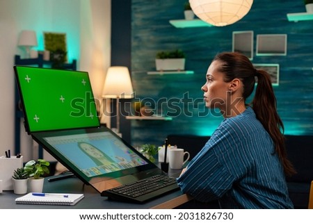Studio editor worker looking at green screen on monitor and editing portrait picture with graphic tools. Woman photographer using chroma key mockup template for digital background display
