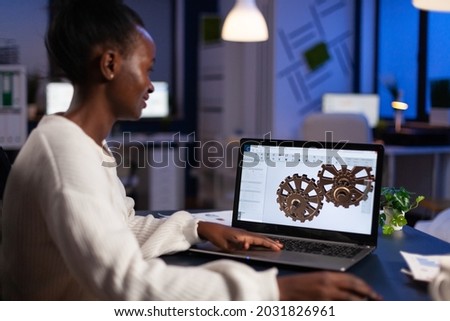 African american architect working industrial new project working at gear prototype late at night in start-up engineering office. Engineer woman developing technical construction product