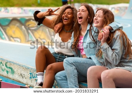 Three teenager skater friends, afro and caucasian, skating and having fun in a skate park