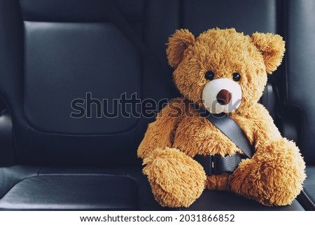 Brown teddy bear wearing car seat belt Royalty-Free Stock Photo #2031866852