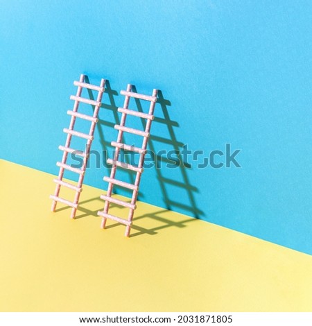 Creative ladder with sunshine shadow against yellow and blue pastel background. Minimal composition.