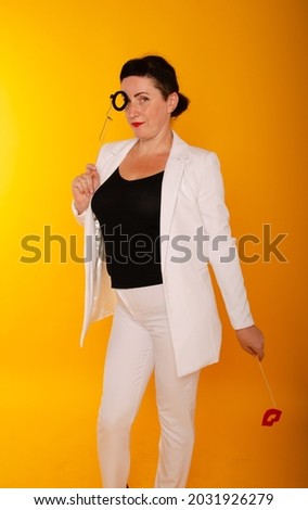 a charming woman with black hair in a white suit with fake lips in her hands, the second hand is empty with room for text. the concept of the leading holiday
