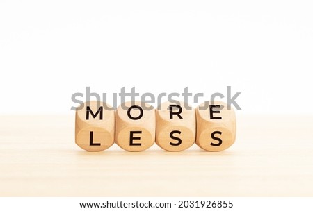 More and less word on changing wooden blocks. Copy space. White background