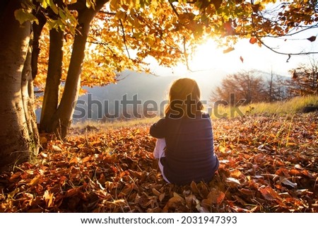 Little girl in magic autum landscape in the sunset. Enjoying, traveling in autumn concept. Royalty-Free Stock Photo #2031947393