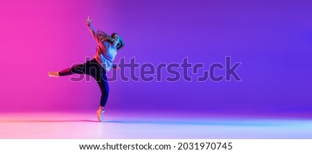 Street dance style. Young beautiful female hip-hop dancer dancing in neon. Sport achievement, spirit of expression. Concept of dance, youth, hobby, dynamics, movement, action, ad