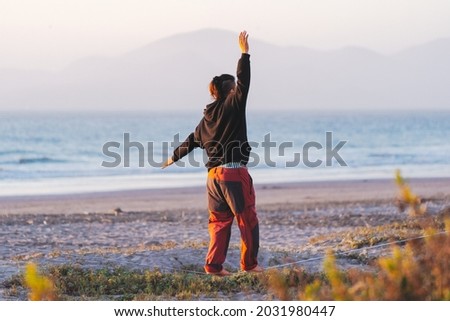 young man walking and balancing on the webbing , slack-lining at the beach