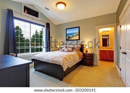 Master bedroom interior with big french window, vaulted ceiling and bathroom.