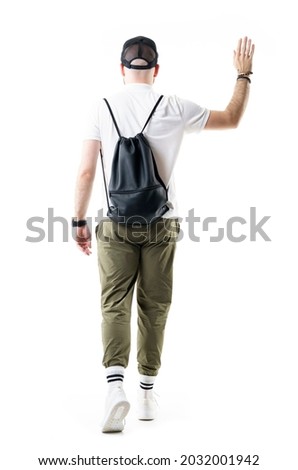 Back view of young stylish man with black bag walking away waving hand goodbye. Full length portrait isolated on white background