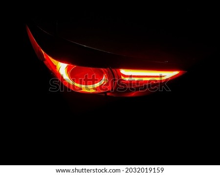 The left back tail light is in dark background, have movement of red color when SUV car parking. It has some raindrop at curve then make feel duty but smart .