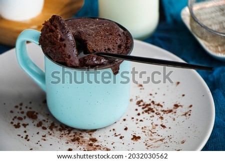 mugcake is microwaved. Homemade cupcake in a mug is on a plate. Chocolate brownie mug cake. Easy cooking concept, microwave baking. muffin chocolate. High quality photo Royalty-Free Stock Photo #2032030562