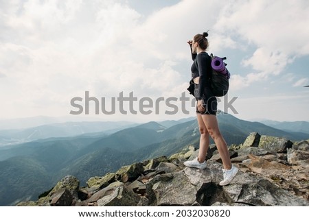 sporty young woman with a backpack on top of the mountain