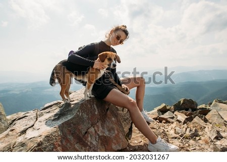 sporty young woman with a dog on top of the mountain Royalty-Free Stock Photo #2032031267