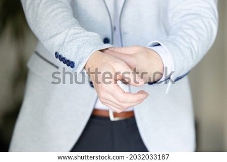 Close up image of a fashion the hands of a young businessman, handsome model man in casual cloth costume. Wearing the vest in the cage, black jeans and blue shirt. High quality photo