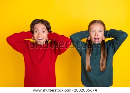 Portrait of attractive amazed cheerful couple closing ears good mood isolated over bright yellow color background
