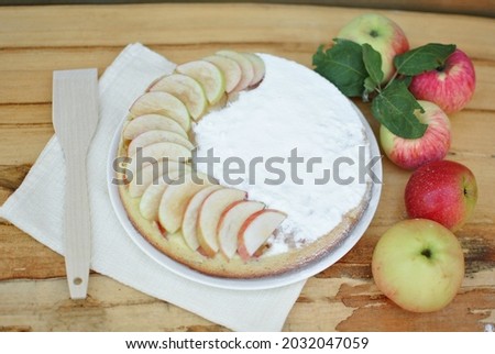 Apple pie and apples on a wooden table.