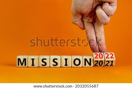 2022 mission and new year symbol. Businessman turns wooden cubes, changes words mission 2021 to mission 2022. Beautiful orange background, copy space. Business, 2022 mission and new year concept.