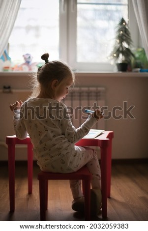 a girl in pajamas writes a letter to Santa Claus at home. Lifestyle, silhouette picture