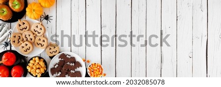 Rustic Halloween treat corner border over a white wood banner background with copy space. Overhead view. Selection of candied apples, cookies, candy and sweets.