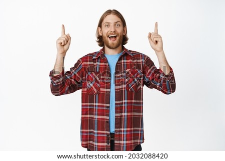 Portrait of happy excited man pointing fingers up, smiling thrilled, showing advertisement upwards, big sale, recommending click on link, show banner, white background