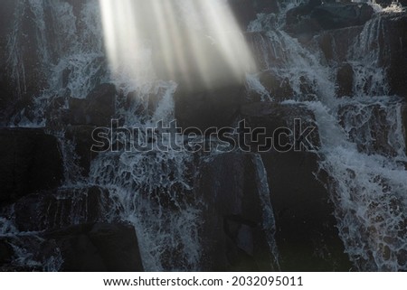 Poetic view of the waterfall. The rocky falls and falling white water with a beautiful sunlight ray.