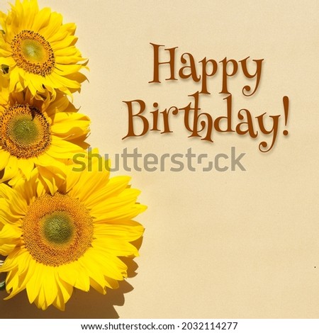 Happy Birthday, text with sunflowers on square flat lay. Beige, yellow paper background. Simple minimal flower border arrangement, square composition.