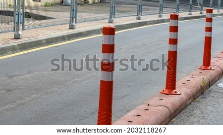 Row of red and white traffic barrier pole on road. A barrier made of plastic columns with reflective pigment on an asphalt road. Danger concept.