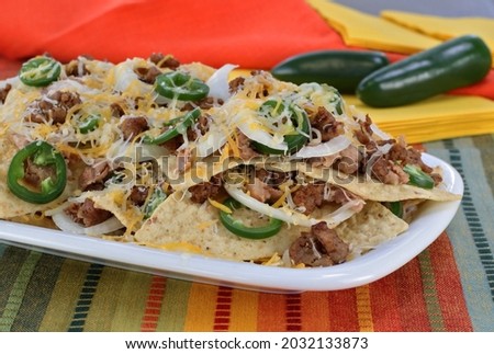 Mexican sausage, bean and cheese nachos on an oval plate.  Macro close up.