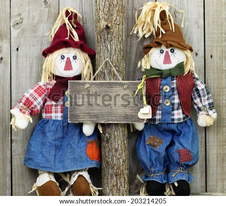 Blank rustic wood sign hanging on tree with boy and girl scarecrows