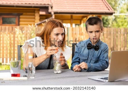 Mom and son are conducting chemical experiments at home. An experience with a child about creating a rocket launcher using a bottle, soda and vinegar.