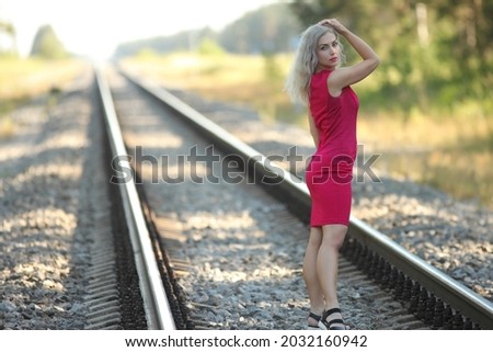 young woman in red dress on the railway