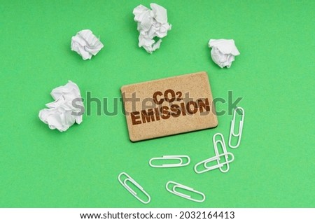 Ecology concept. On a green background, crumpled paper, paper clips and a sign with the inscription - co2 emission