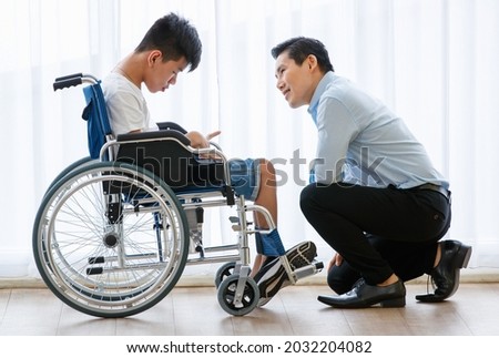 Asian doctor talking, support, and encouragement to a young disabled boy in a wheelchair.