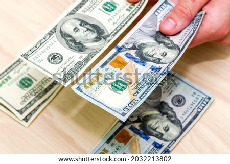 a man puts hundred-dollar bills into two piles on the table. High quality photo
