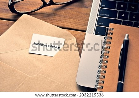 There is a laptop, a pen, an envelope, and a card with Mobility as a service written on it.