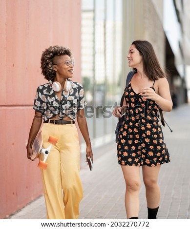 two friends in casual clothes walking through the city, multi-ethnic friends